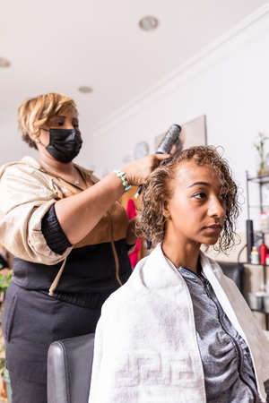 Makeover haircut in beauty salon with Latin hairdresser professional. mixed race with facemaskの写真素材