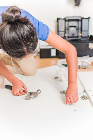 Latin Bolivian strong and independent success woman assembly and repair furniture with hammer.
