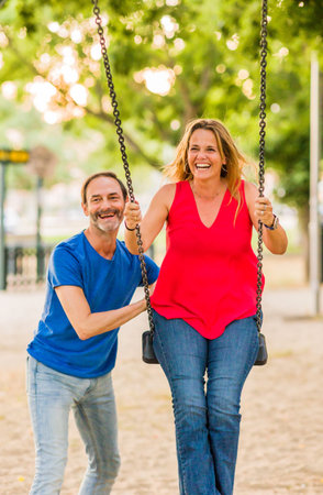 married mature 50s couple enjoy happy in playground swing. Seniors freedom love and happinessの写真素材