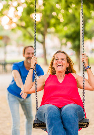 married mature 50s couple enjoy happy in playground swing. Seniors freedom love and happinessの写真素材