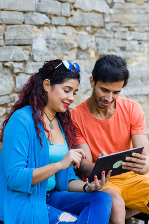 mixed race couple together in Villanueva Asturias using tablet technology outdoors on holydayの写真素材