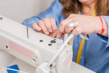 Atelier process needle detail. Unrecognizable woman hand on a sewing machine doing handmade fabric