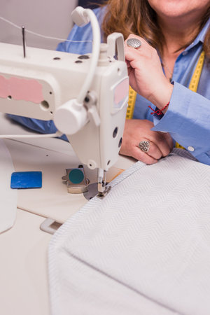 Atelier process needle detail. Unrecognizable woman hand on a sewing machine doing handmade fabricの写真素材