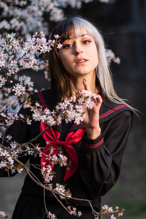 hispanic lolita with japanese school cosplay uniform witth beautiful cherry blossom backgroundの写真素材