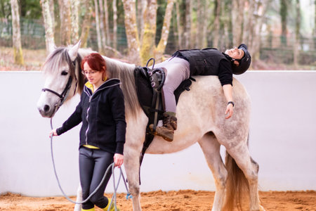 Hippotherapy. Therapeutic wellness, occupational therapy mid-adult woman patient on horse schoolの写真素材