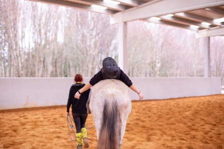 Hippotherapy. Therapeutic wellness, occupational therapy mid-adult woman patient on horse schoolの写真素材