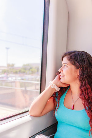 Train traveler. Hispanic mid-adult woman looking through the window on holiday lifestyle vacationの写真素材