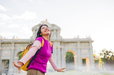 Happy latin american student enjoying her trip to puerta de alcala in madrid, spainの写真素材