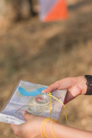 Unrecognizable Woman using compass and map during orienteering race.