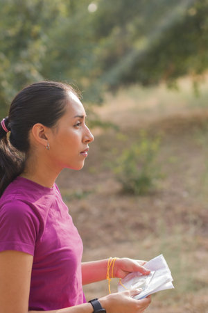 Young latin woman navigating with map and compass during orienteering race. Latin young venezuelanの写真素材