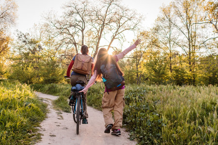Happy women walking and cycling in nature at sunsetの写真素材