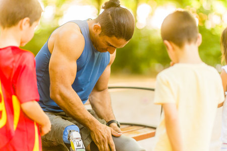 Disabled Middle-aged athlete inspiring children with prosthetic legの写真素材