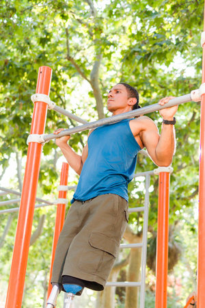 Latin Mid-Man with prosthetic leg doing pull ups in park