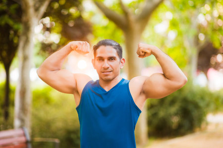 Strong latin man flexing muscles in park