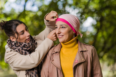 Daughter helping mother with headscarf, breast cancer awarenessの写真素材
