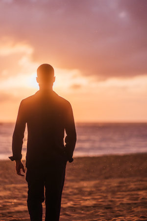 Man silhouetted against sunset sky at beach