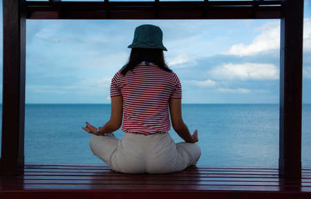 The girl is meditating. On the small pavilion by the sea.の写真素材