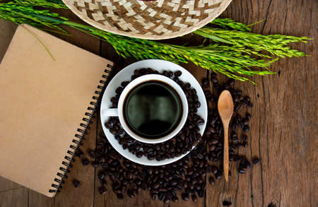 Roasted coffee beans and cup notebook Rice and hat on the old wooder floorの写真素材