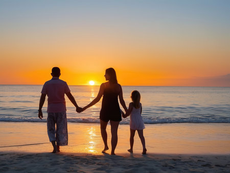 Happy family walking on the beach at sunset. Mother, father and little daughterの素材
