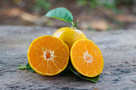Bright orange slices on weathered wooden floor, rustic texture and minimal natural composition.の写真素材