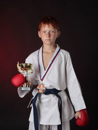 Bronze medalist of with a medal on his chest keeps a cup while wearing gloves の写真素材