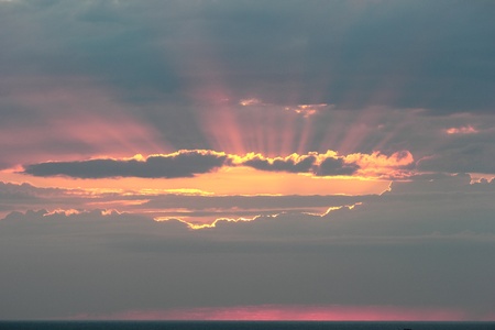 The rays of the sun make the way through clouds over the Black Sea during sunset の写真素材