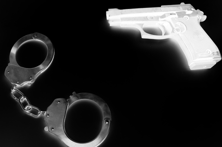 Black and white negative photo of crime symbols handcuffs and gunの写真素材