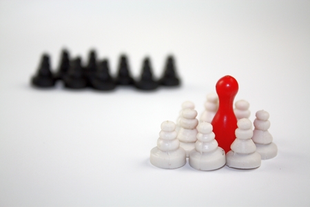 Fear from the others concept with white and dark chess pieces and one red leader.の写真素材