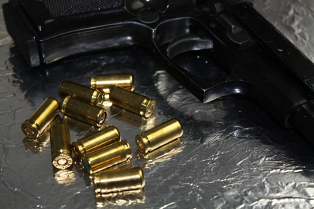 Pistol gun detail with brass golden munition on shiny silver deskの写真素材
