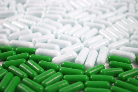 Bright green capsules medical tablets in front and white medicaments behindの写真素材
