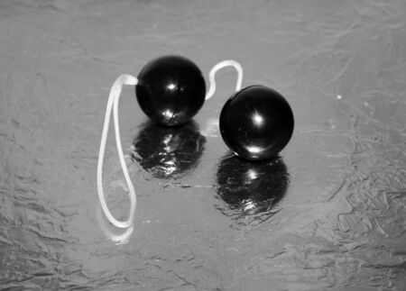 Simple cheap black vaginal love balls on silver shiny surface. Sex toy object.の写真素材