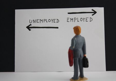 Businessman miniature person stands before the inscriptions unemployed and emploÃ½ed with arrows. Jobless concept.の写真素材