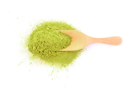powdered matcha green tea in wooden spoon isolated on white background
