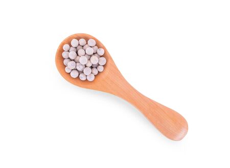 white Pepper seeds in wooden spoon on whiteの写真素材