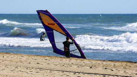 Athlete transporting windsurfing equipment