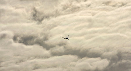 Commercial plane moving away between storm clouds