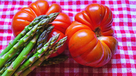 Tomato, green asparagus, peppers and celery on red and white checkered tableclothの写真素材