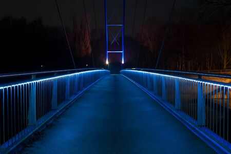 night photograph of a glowing blue pedestrian bridgeの写真素材