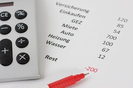 Closeup of a calculator and a red pen along with a negative budget planningの写真素材