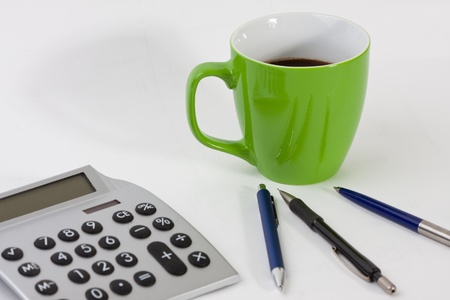Close-up of a desk with a cup, pens and a calculatorの写真素材