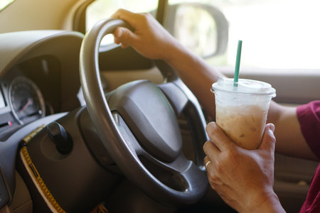 Closeup hand hold cup of iced coffee to drink in car. Concept, baverge for refreshing or helping to awake from asleep during driving that can cause car accident.の写真素材