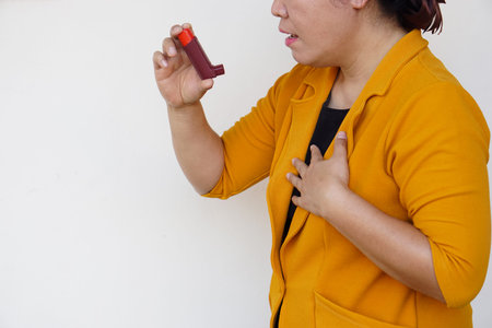 Closeup female patient uses brown asthma inhaler for relief asthma. Concept : Health care at home. ...