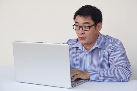 Asian man feels surprised and excited during surfing internet on laptop computer. Concept : Emotional expression. Omg.Wow. feeling. Online working, working with data.の写真素材