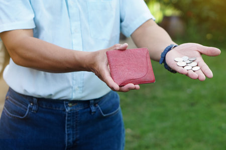 Closeup hand holds Thai baht coins and empty wallet. Concept, no money, economic crisis. Financial problems. Broke or less money at the end of month.の写真素材