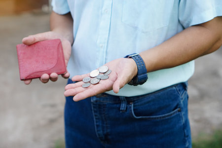 Closeup hand holds Thai baht coins and empty wallet. Concept, no money, economic crisis. Financial problems. Broke or less money at the end of month.の写真素材