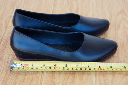 Closeup black shoes for woman and measuring tape. Concept, measurement size of shoes. Footwears.の写真素材