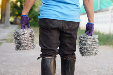 Closeup worker hand holds rolls of barbed wire. Concept, construction tool. Barbed wire is used for make fences , secure property ,make border to show the territory of  area.の写真素材