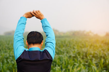 Back view of man workouts  outdoor, stretching arms up.Warm up before or cool down after exercise. Concept, health care.  Sport , creative activity. Give time for yourself.の写真素材