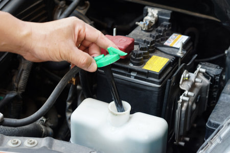 Mechanic's hand is opening bottle of water in car engine to Check auto car's coolant level. Concept...