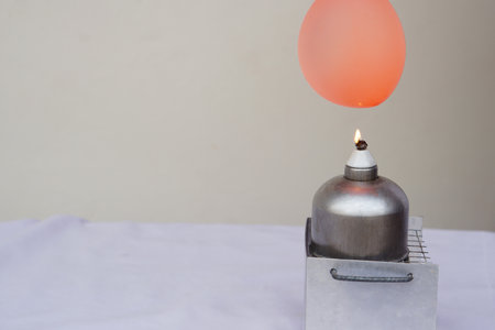 Balloon with water filled is burned on fire flame of metal lantern. Concept, science experiment. Fireproof balloon demonstration. Balloon with water inside doesn't pop under flame.の写真素材